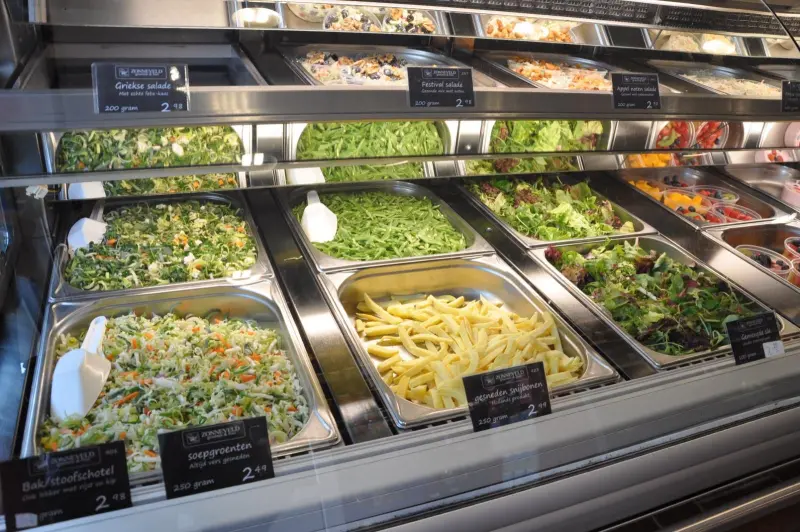 Vitrine met bakken verse salades en gesneden groente